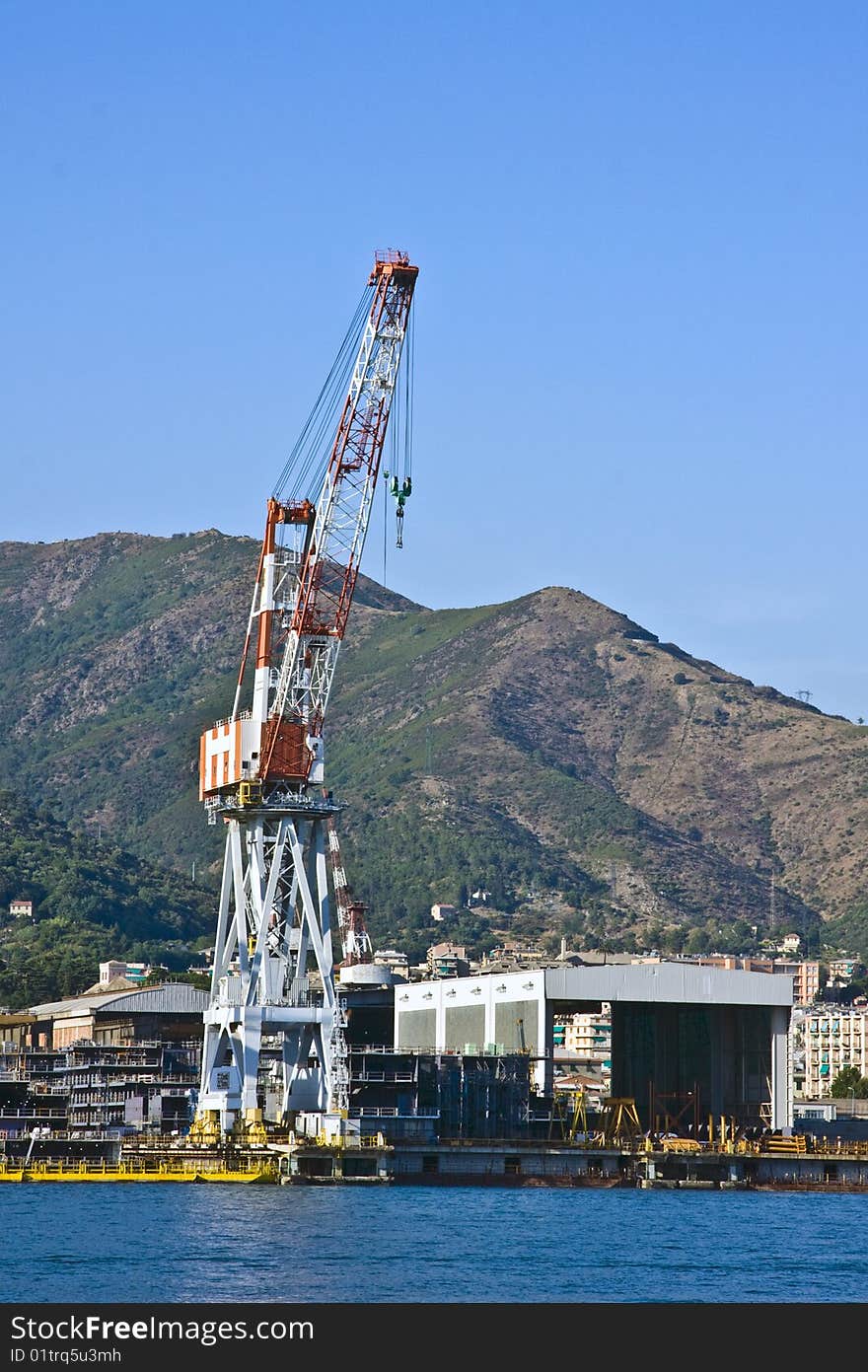 The quay of the port of Genoa and the hills on background. The ship yards are a major resource of the Genoese economy. In this shot a big crane ship. The quay of the port of Genoa and the hills on background. The ship yards are a major resource of the Genoese economy. In this shot a big crane ship.