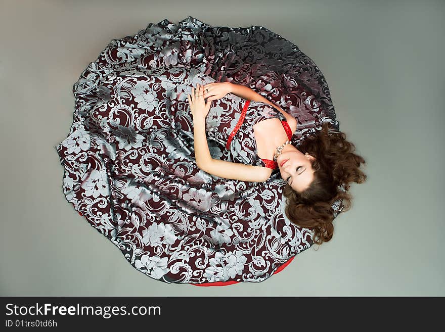 Extravagant young lady on color dress laying on floor with eyes closed separated