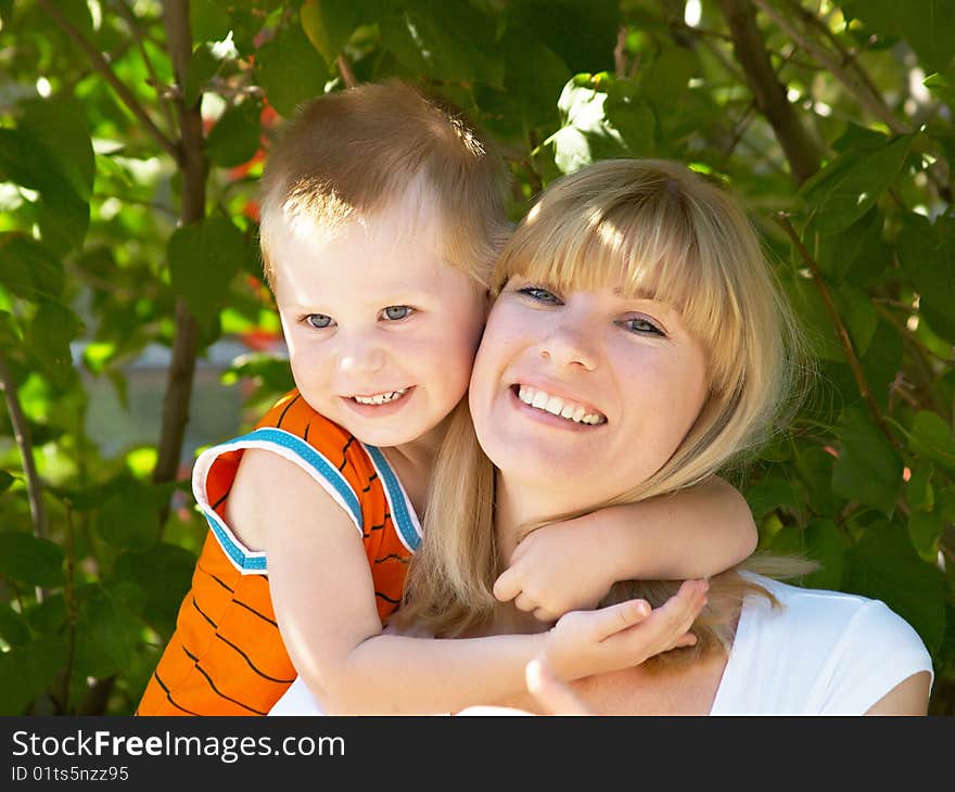 Woman and young boy outdoors embracing and smiling. Woman and young boy outdoors embracing and smiling