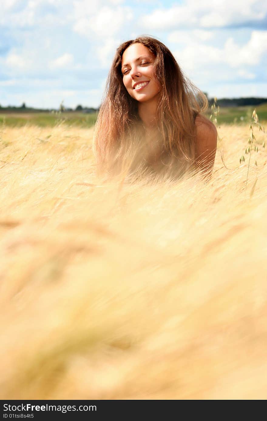 Beautiful young woman relaxing in golden field. Beautiful young woman relaxing in golden field