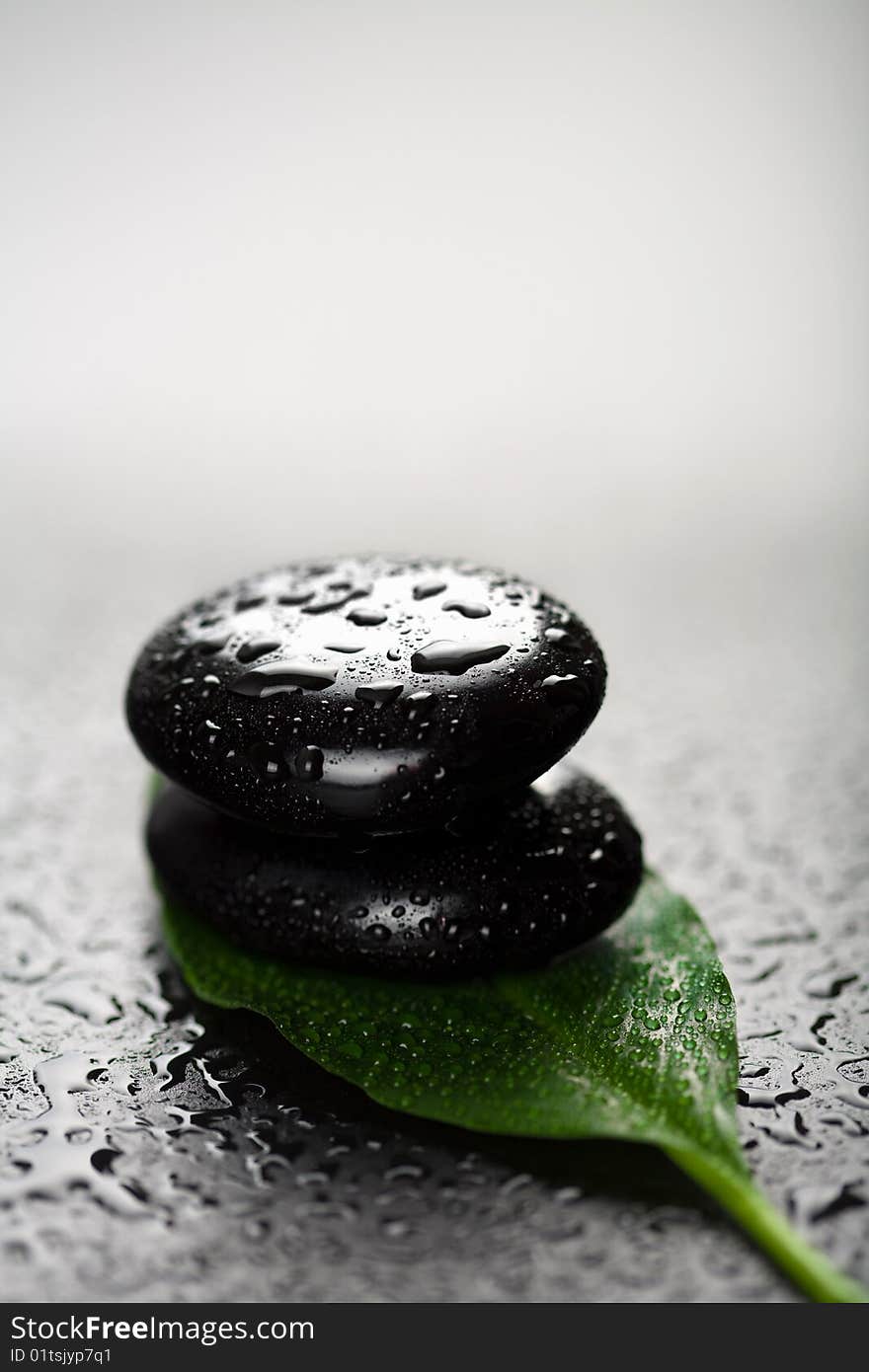 Black spa stones and leaf with water drops