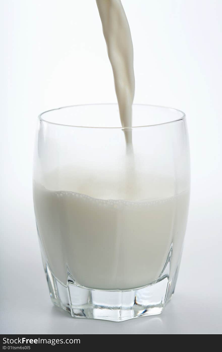 Fresh milk pouring into glass isolated