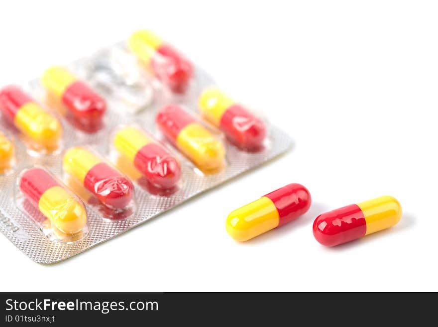 Red and yellow capsule pills in blister isolated over white