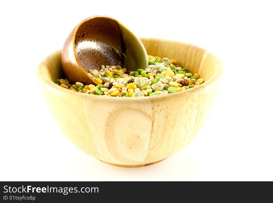 Assorted soup pulses in a small wooden bowl with other small green and brown bowl on a white background