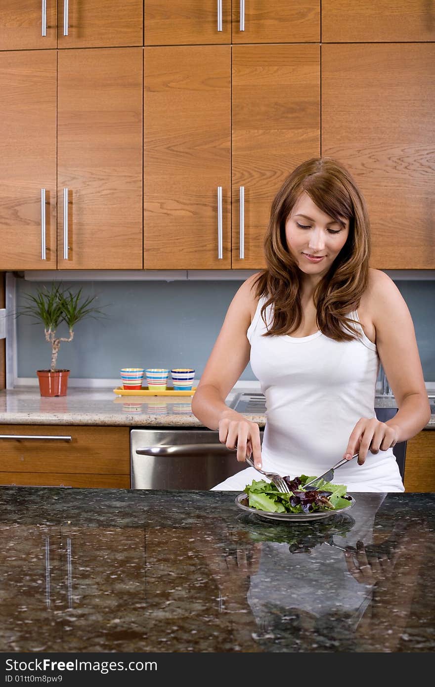 Woman eating a salad in a modern kitchen