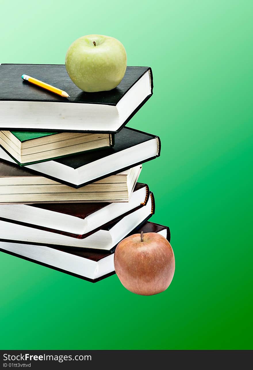 Green apple and pencil on books