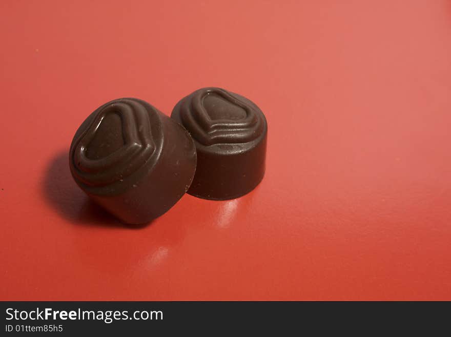 Pair of chocolate sweets with the image of heart on a red background