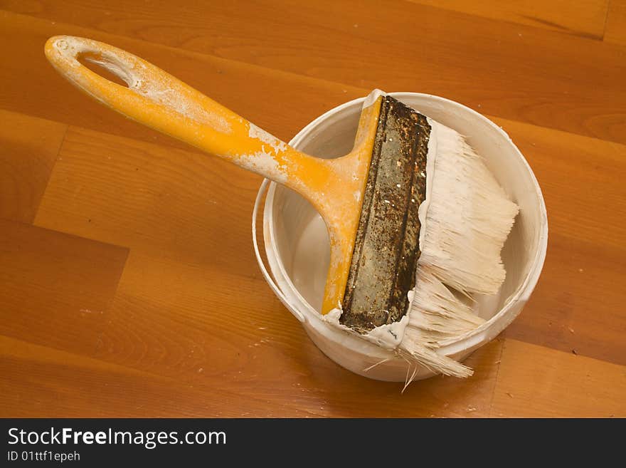 Paintbrush and bucket with paint on wooden table