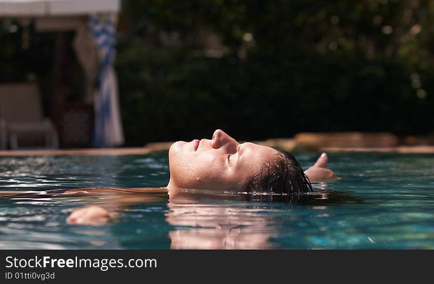 Young woman in a beautiful pool with palms in the background. Young woman in a beautiful pool with palms in the background.