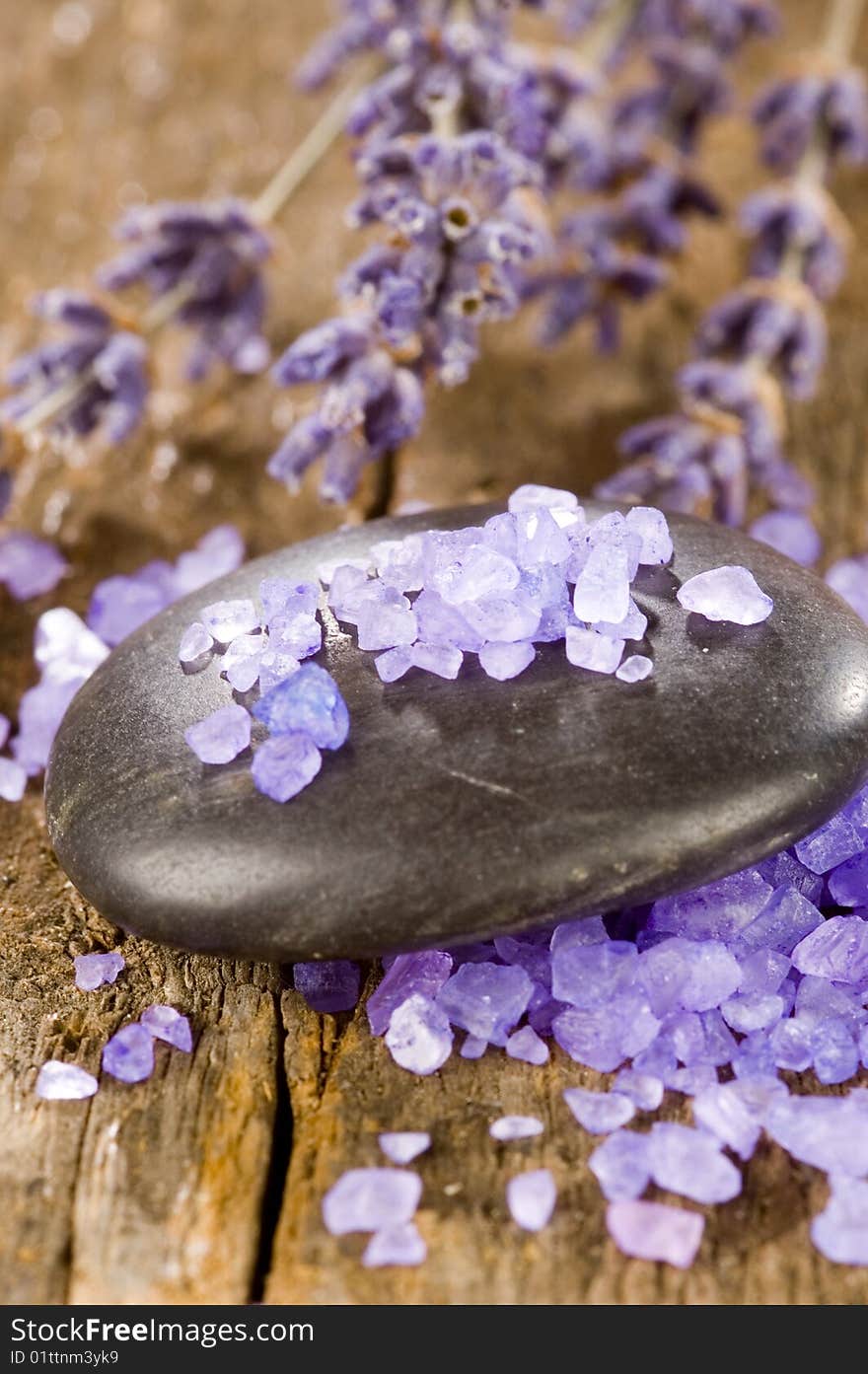 Black spa stones with salt and lavender on a wooden table