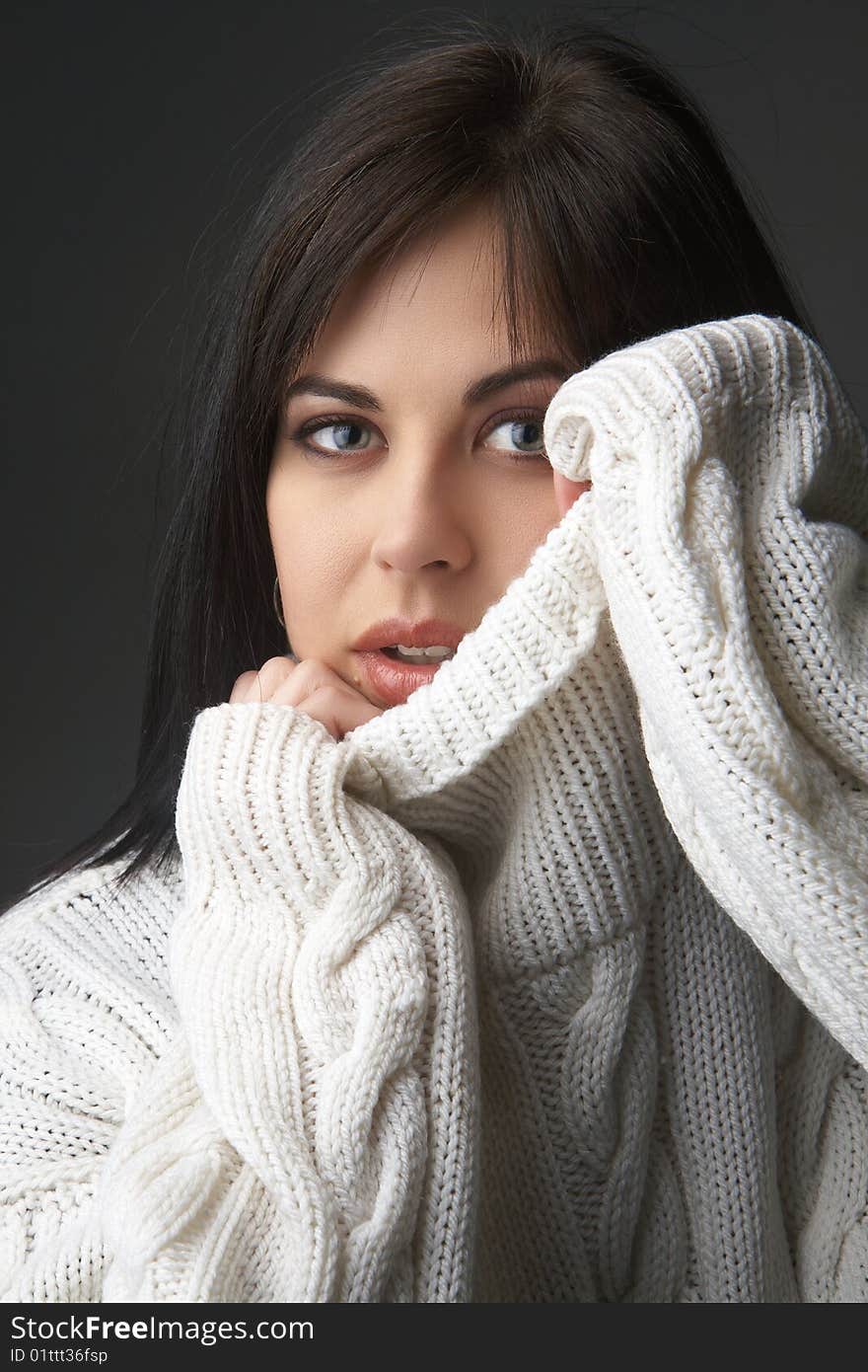 Portrait of a beautiful young brunette woman wearing a white oversized jersey on black background. Portrait of a beautiful young brunette woman wearing a white oversized jersey on black background