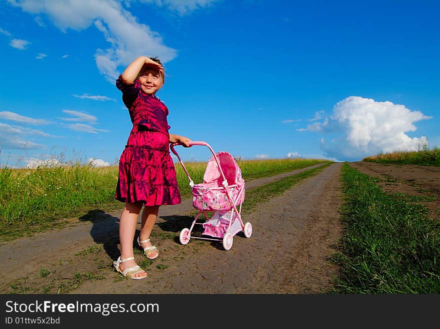 The little girl on a farmer field with carriage. The little girl on a farmer field with carriage