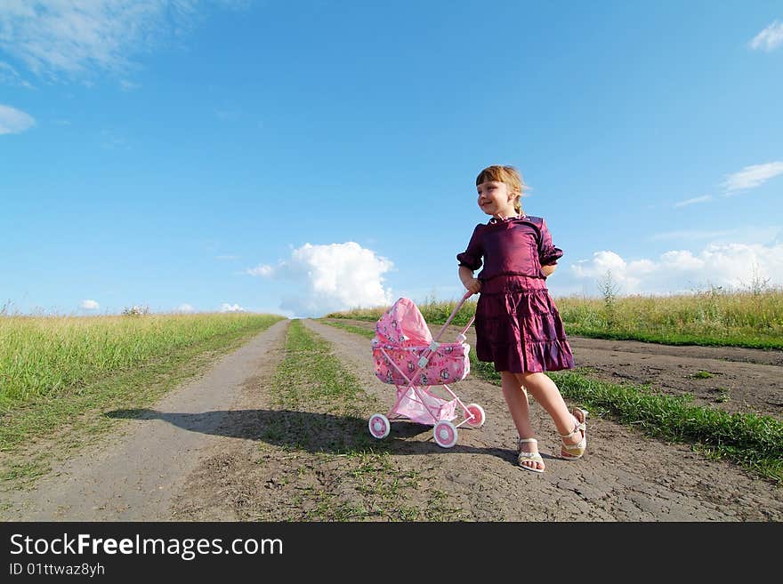 The little girl on a farmer field with carriage. The little girl on a farmer field with carriage