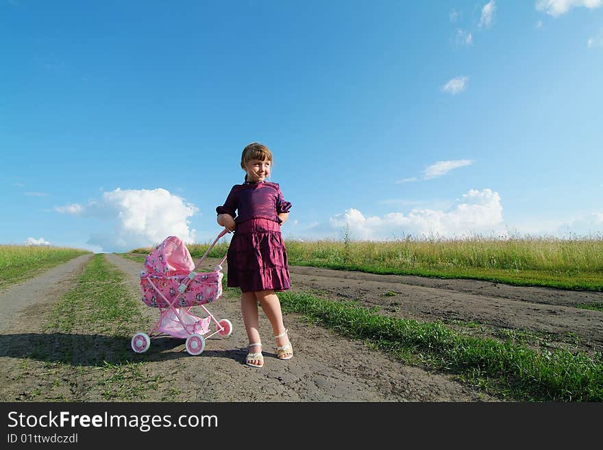 The little girl on a farmer field with carriage. The little girl on a farmer field with carriage