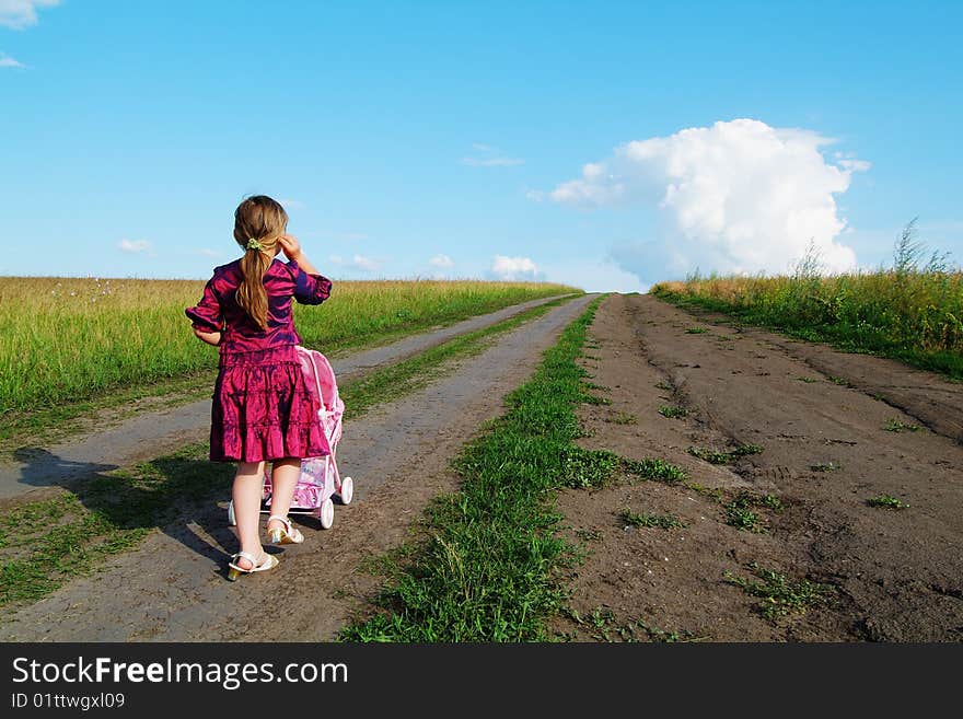 The little girl on a farmer field with carriage. The little girl on a farmer field with carriage