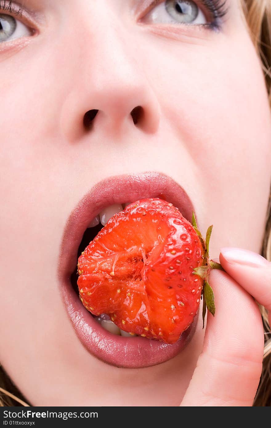 Pretty female model eating tasty strawberry