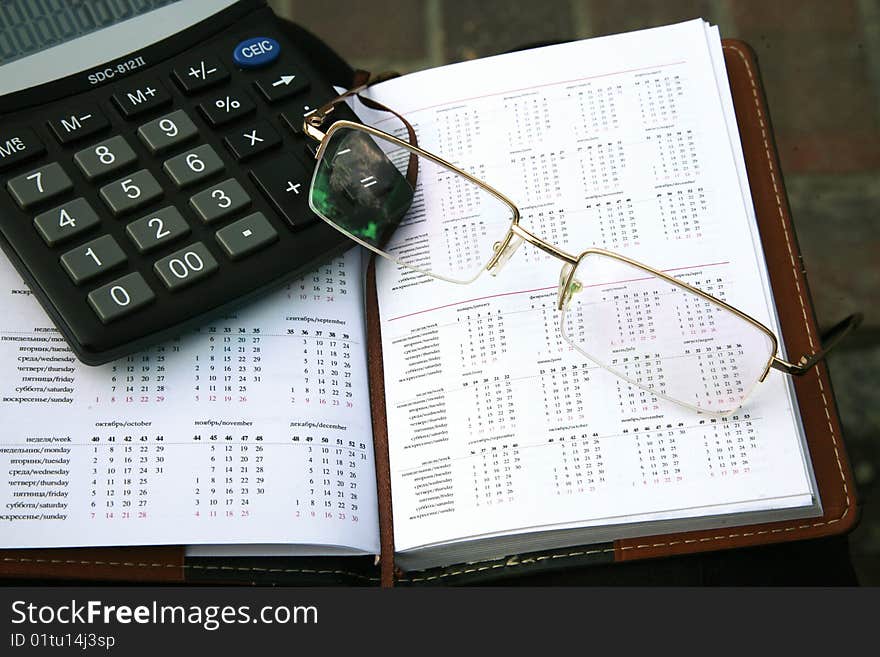 Business still-life with glasses, calculator and organizer