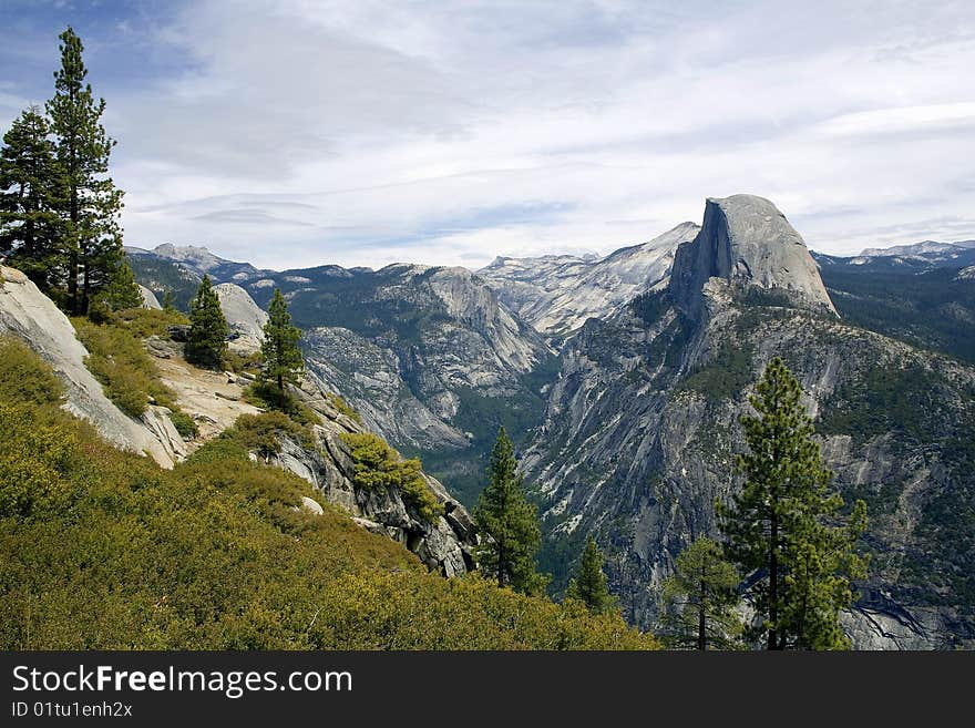 View of Half Dome with Mountains in the background and trees in the foreground. View of Half Dome with Mountains in the background and trees in the foreground