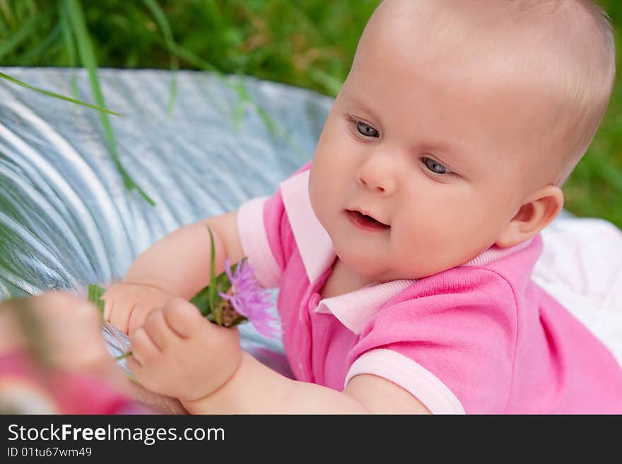 The little girl in pink clothes pulls a hand to a flower