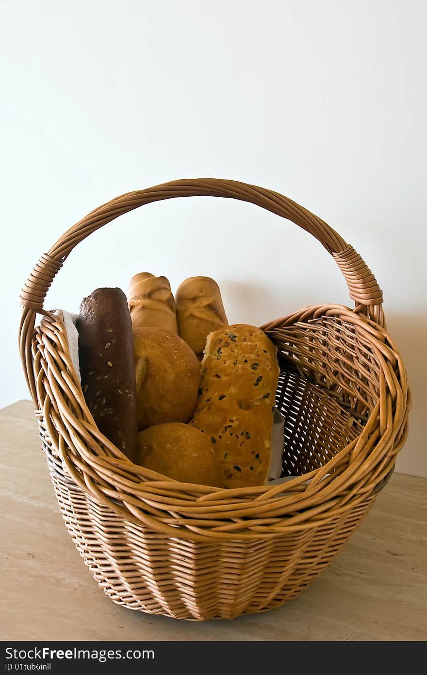 Basket with the bread, containing two white bread, two baguets, black bread with caraway seeds and a roll with raisin. Basket with the bread, containing two white bread, two baguets, black bread with caraway seeds and a roll with raisin