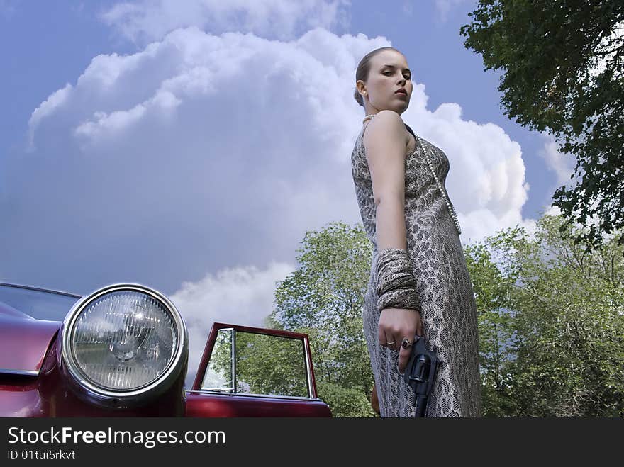 Beautiful stylish girl with a revolver in a hand at the car. Beautiful stylish girl with a revolver in a hand at the car