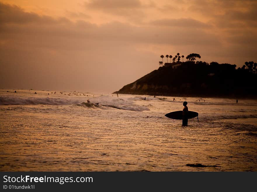 A surfer heads our at sunset for a surf session. A surfer heads our at sunset for a surf session.