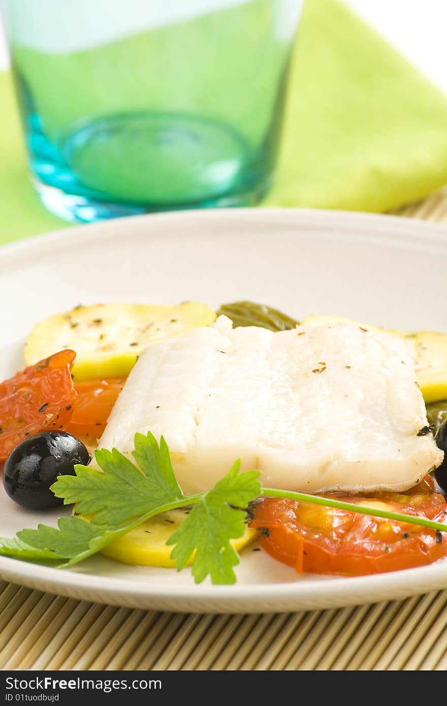 Fillet of cod baked tomatoes zucchini black olives isolated