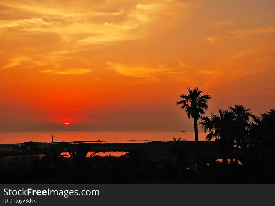 Serene tropical sunset with sun setting into the ocean water