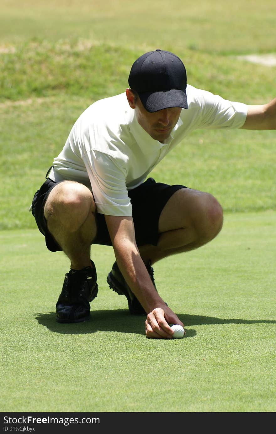 Man on golf course setting ball ready to putt. Man on golf course setting ball ready to putt