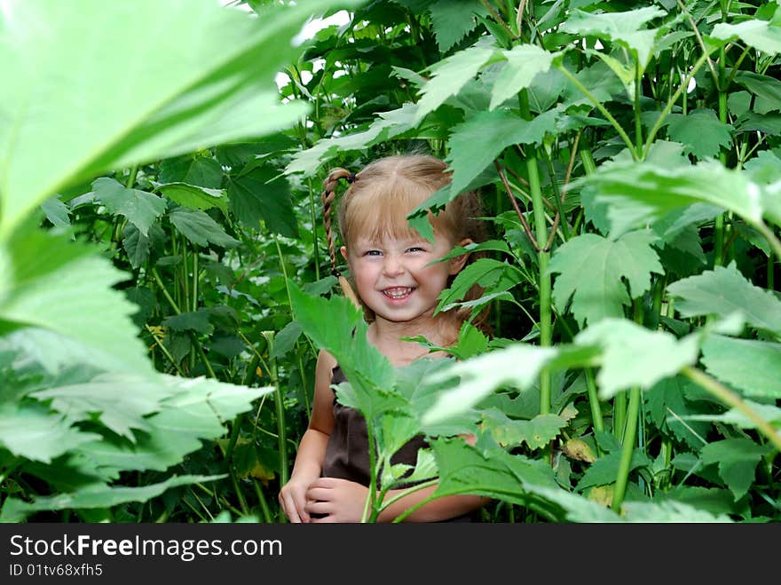 Girl standing in tall green plants with big smile on her face. Girl standing in tall green plants with big smile on her face.