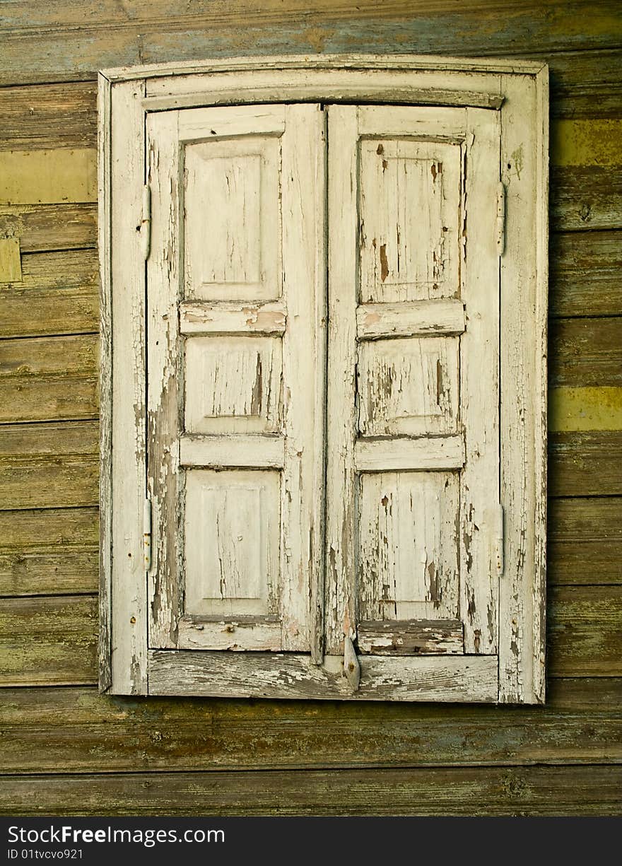 Old window with the closed shutters on a wooden wall