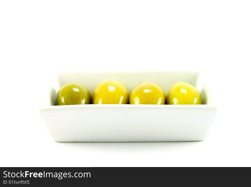 Four green olives in a small dish on a white background. Four green olives in a small dish on a white background