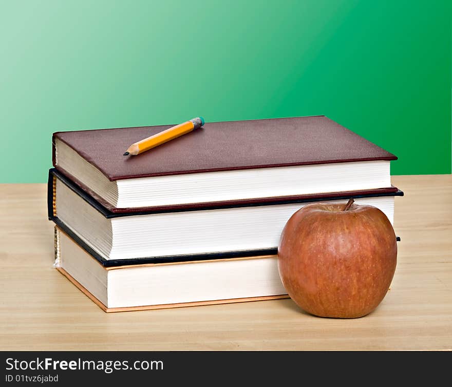 Apple and pencil on top of books