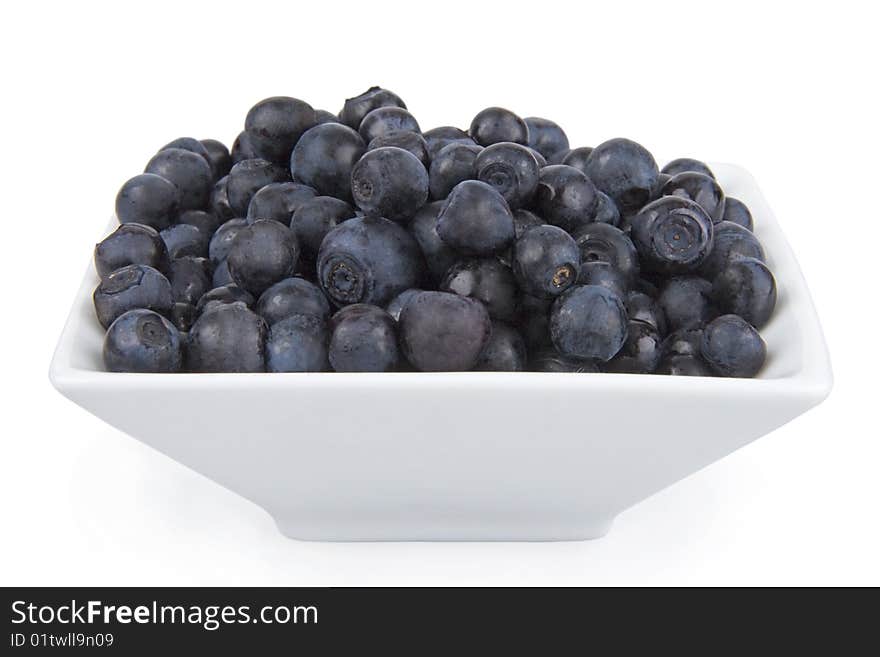 Ripe bilberries in saucer on white background.