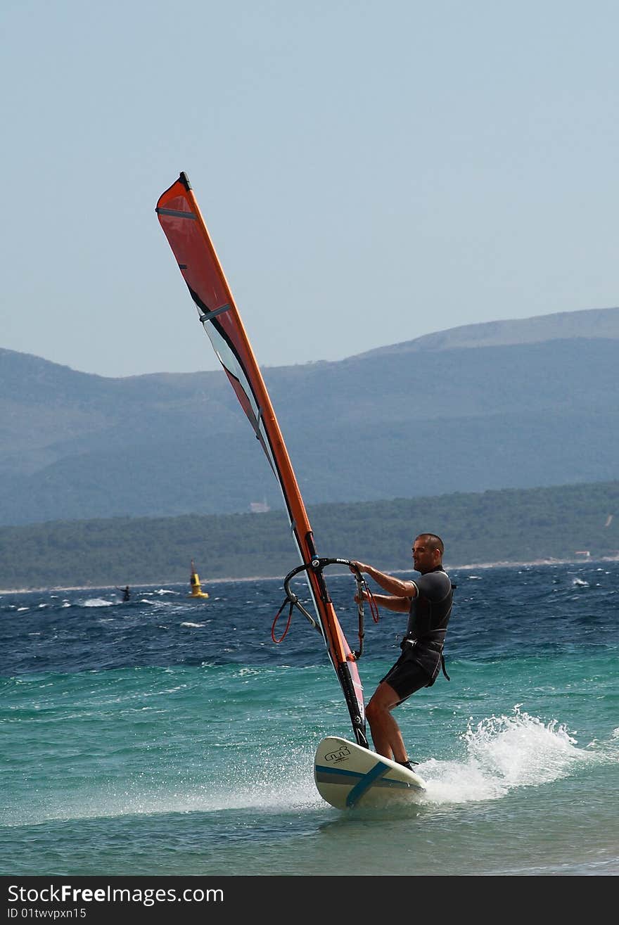 A front picture of a man, surfing @ Zlatni Rat beach, Brac island, Croatia. A front picture of a man, surfing @ Zlatni Rat beach, Brac island, Croatia