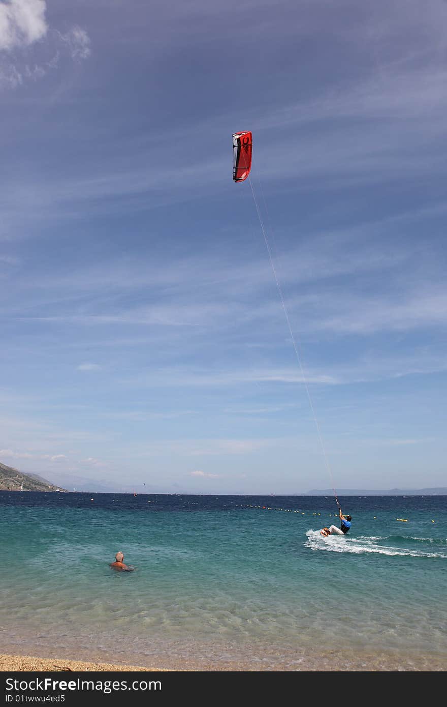 A picture of a man, kiteboarding in a bathing zone @ Zlatni Rat beach, Brac island, Croatia. A picture of a man, kiteboarding in a bathing zone @ Zlatni Rat beach, Brac island, Croatia