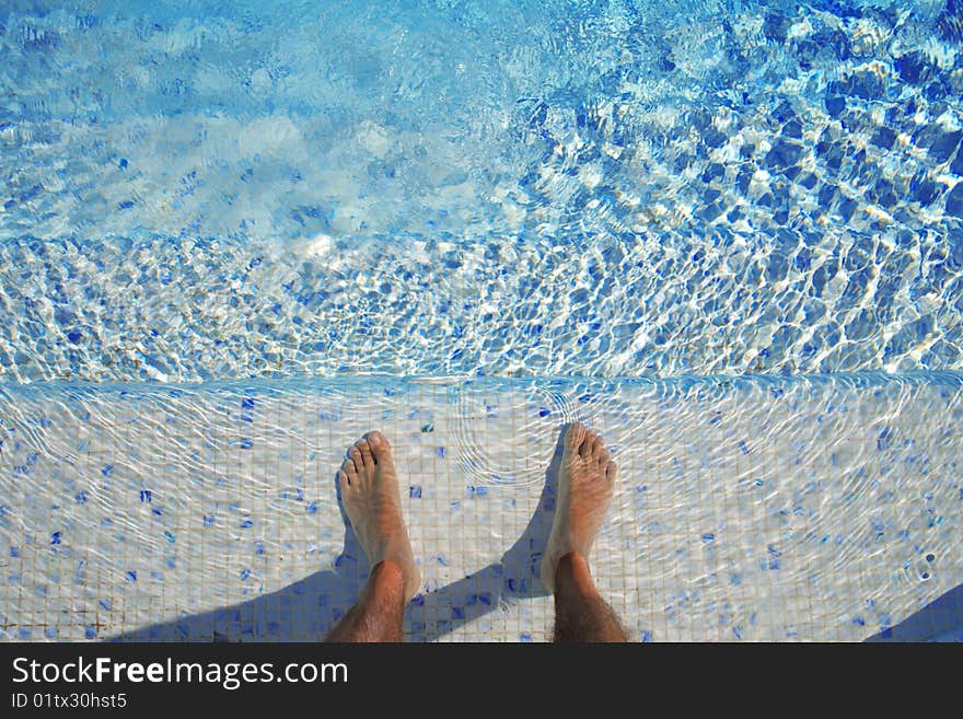 Feet in the water of a swimming pool