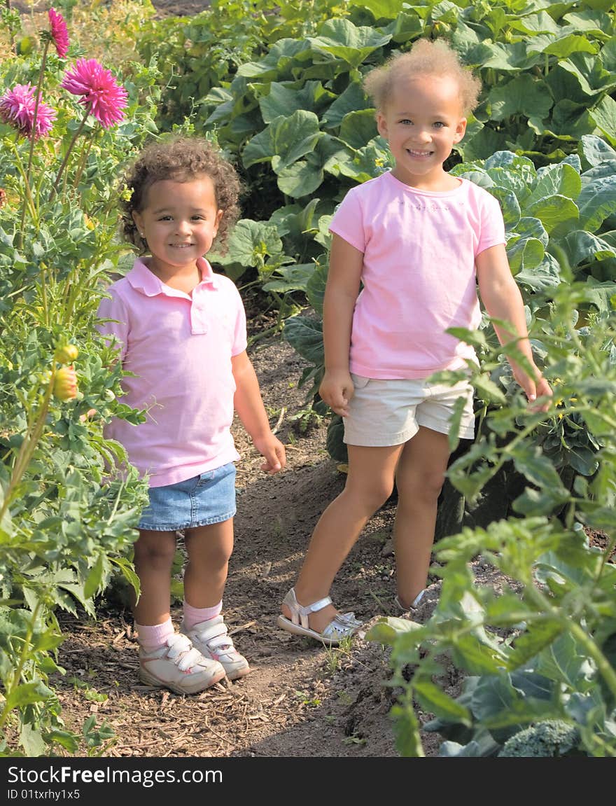 Two beautiful ethnic sisters Little girls in the garden are wearing pink shirts and have adorable smiles.