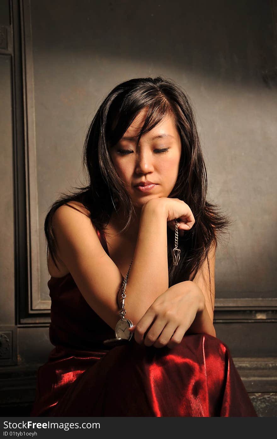 Beautiful young Asian woman in red dress sit and thinking. Beautiful young Asian woman in red dress sit and thinking.