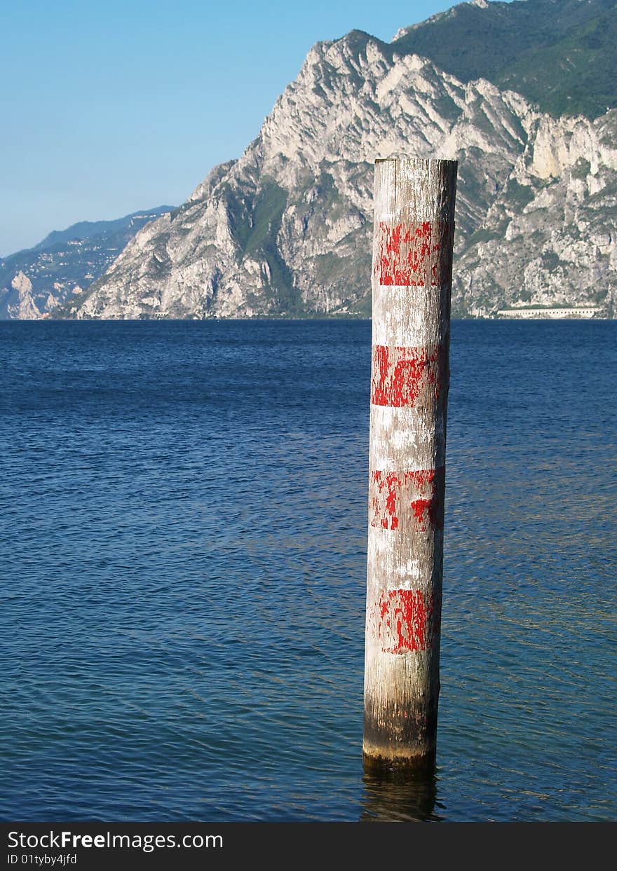 Red and white wooden pole in Lake Garda, Italy