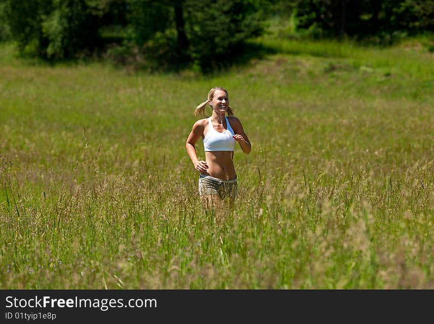 Summer - Young woman jogging in a meadow