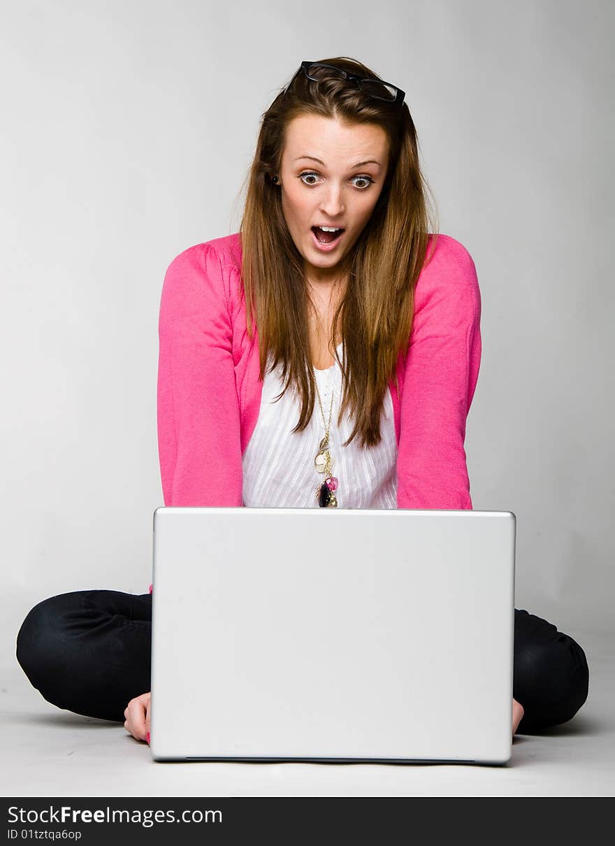 Attractive young woman shocked and frustrated with her laptop against neutral background. Attractive young woman shocked and frustrated with her laptop against neutral background