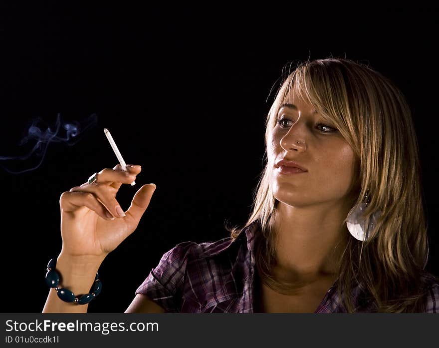 Young woman smoking against dark background