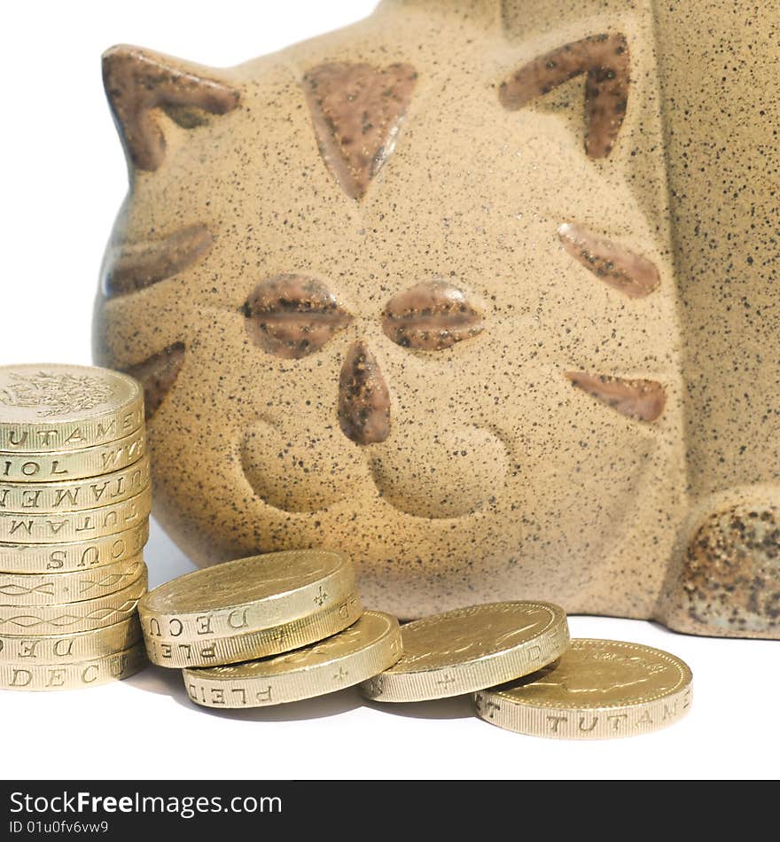 Pile of coins in front of cat shaped piggy bank. Pile of coins in front of cat shaped piggy bank