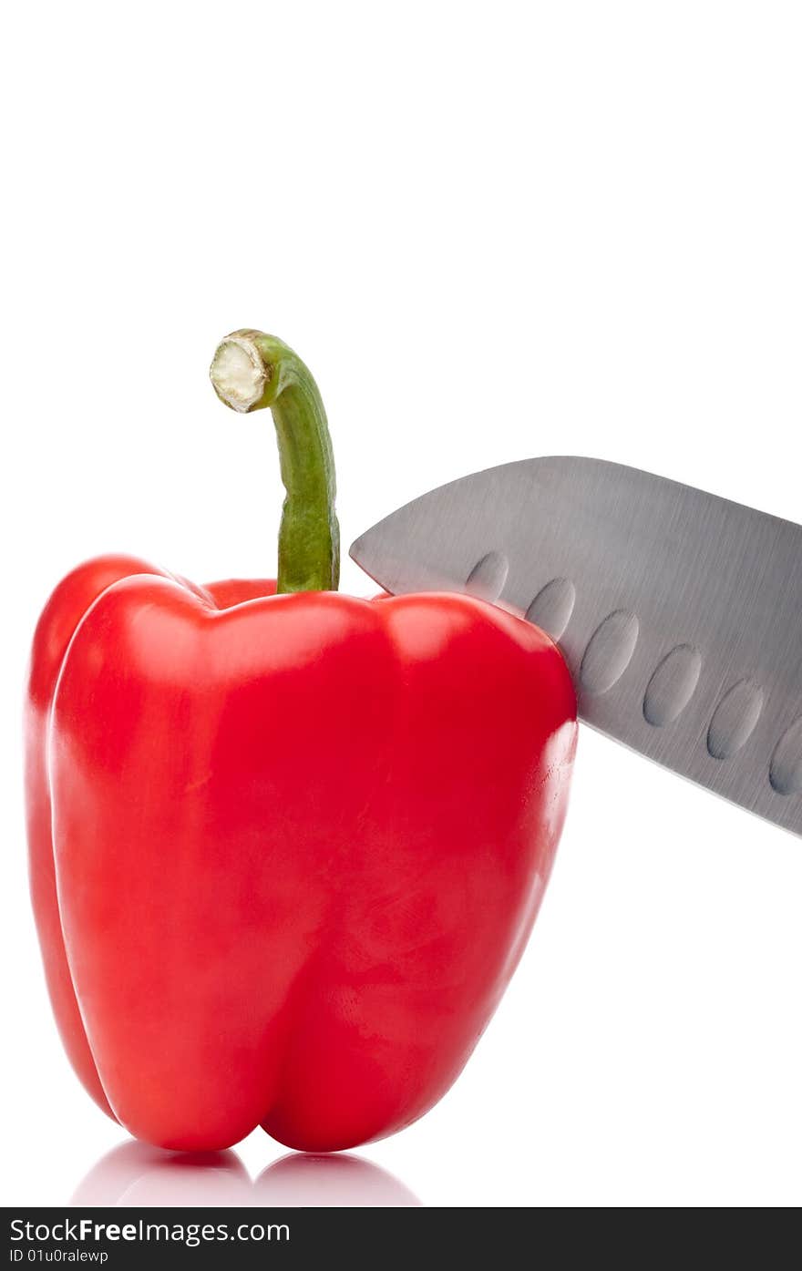 A vertical image of a red pepper being sliced on white