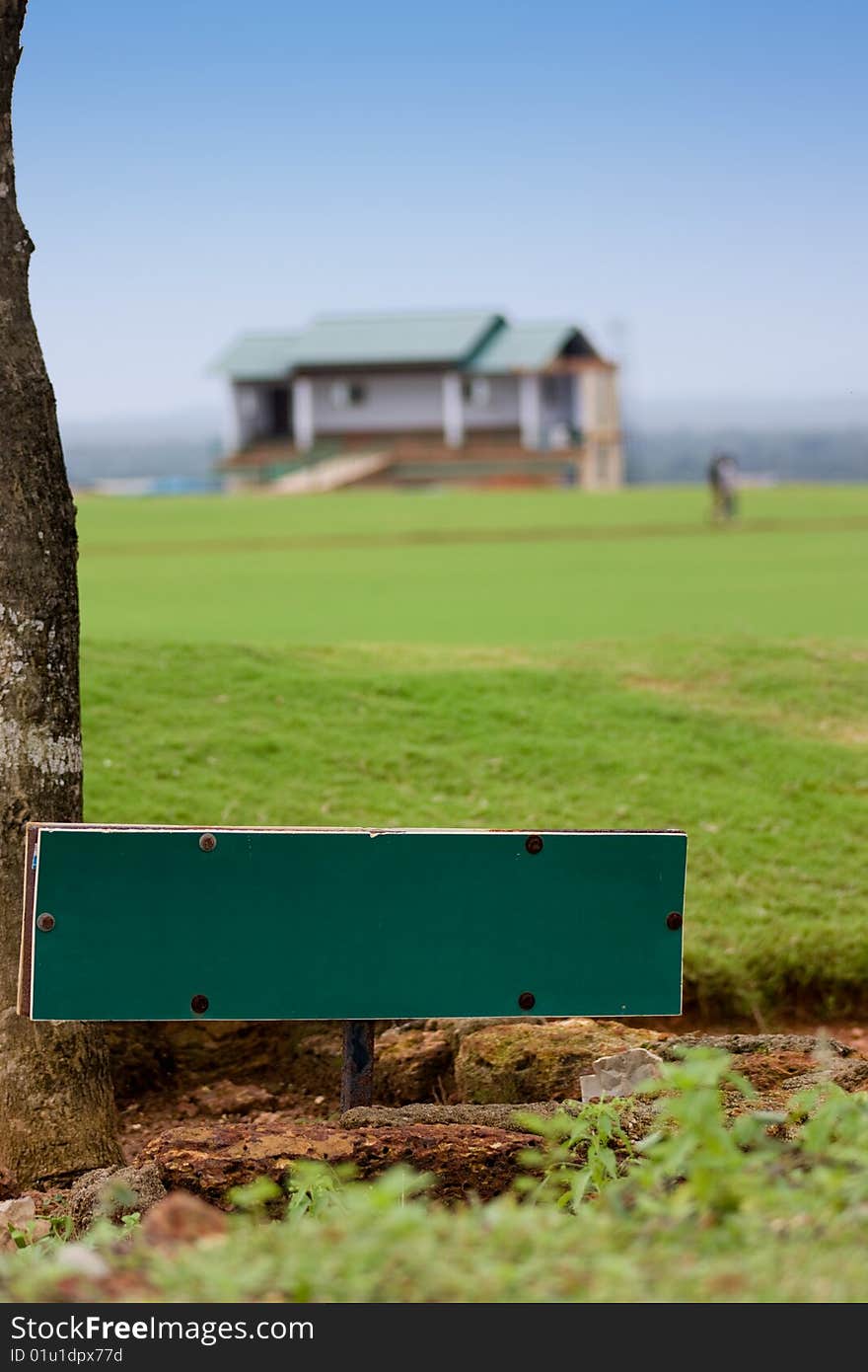 Green Signboard on the grassland having a house. Green Signboard on the grassland having a house