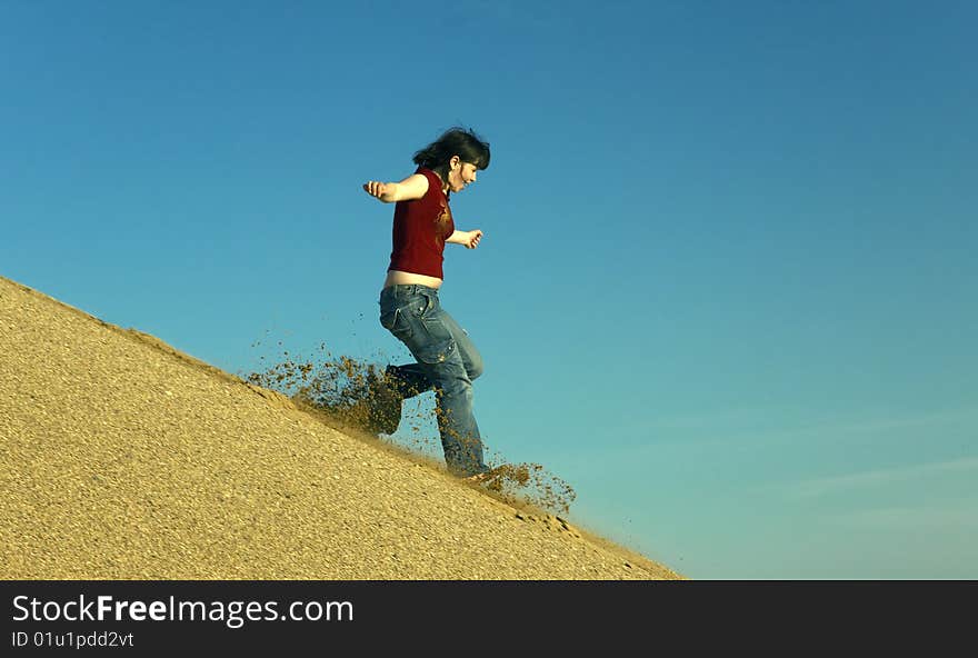 Woman barefoot running down a sand dune