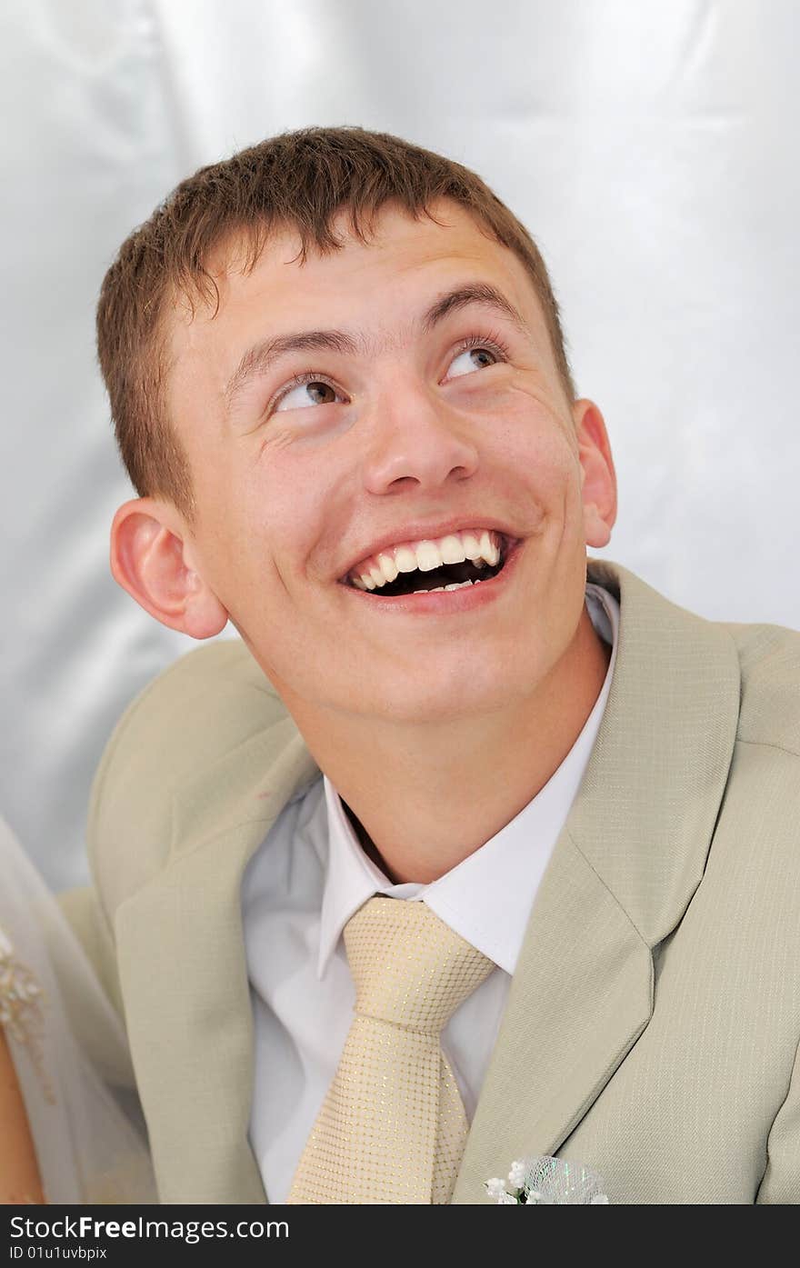 The young beautiful groom has fun behind a wedding table. The young beautiful groom has fun behind a wedding table.