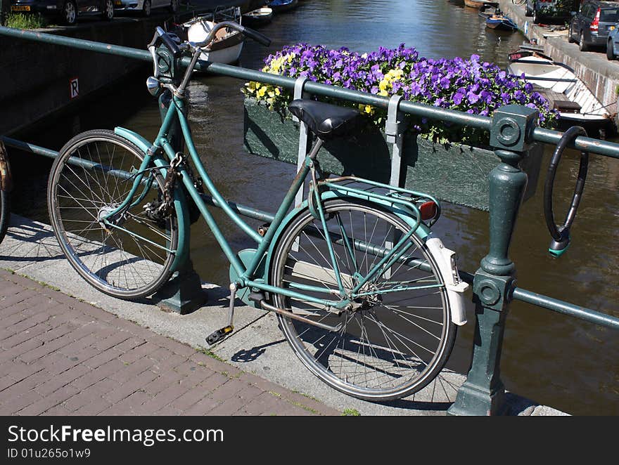 Bike locked to a bridge over a canal in Amsterdam. Bike locked to a bridge over a canal in Amsterdam