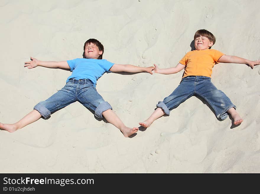 Two children lying nearby on sand